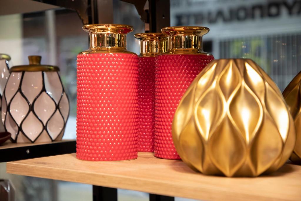 three red and gold vases sitting on a shelf at The Pinnacle Athens in Athens