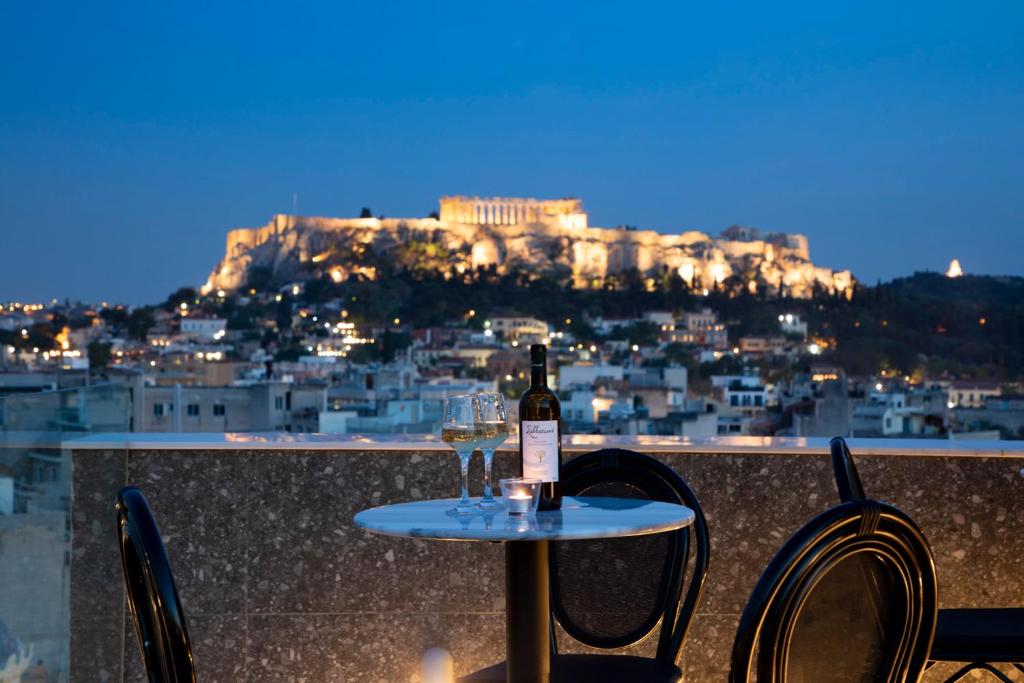 una bottiglia di vino seduta su un tavolo con due sedie di The Pinnacle Athens ad Atene