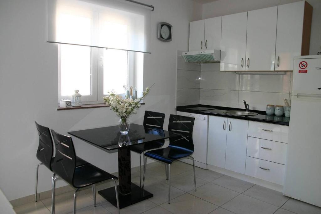 a kitchen with a black table and black chairs at Vicy Apartment Novalja in Novalja