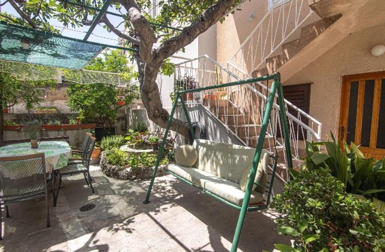 a swing in a garden with a table and a tree at Apartmani Marko in Makarska