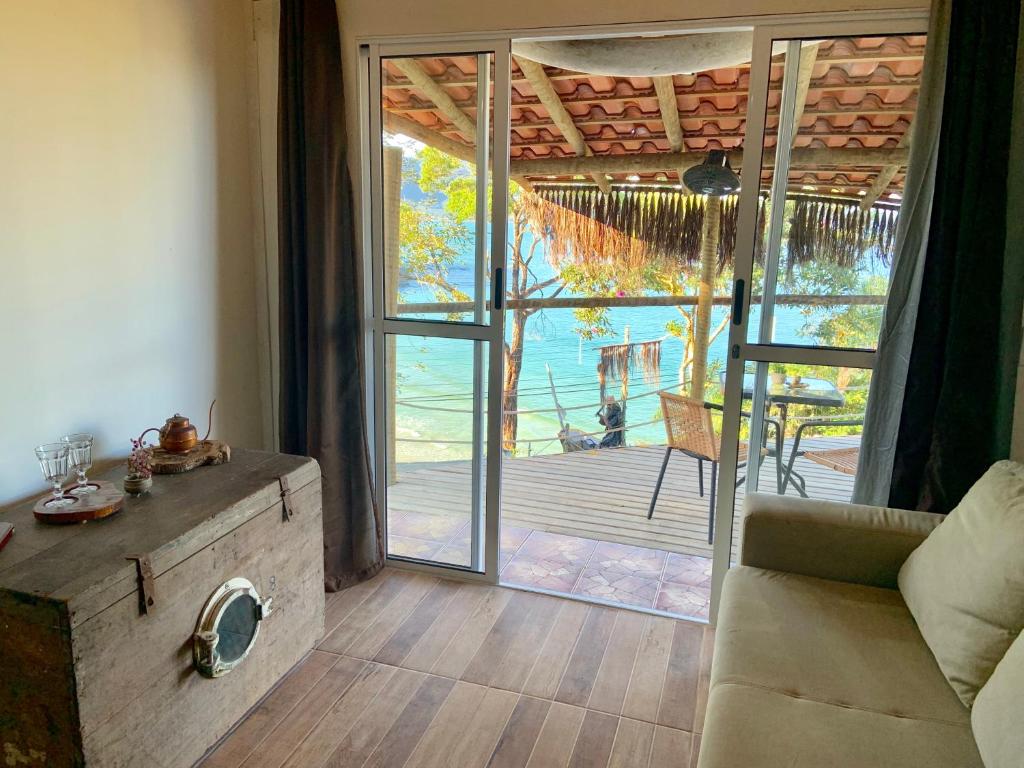 una sala de estar con una puerta abierta a una terraza en Mirante do Pirata Suítes Bed and Breakfast, en Ubatuba