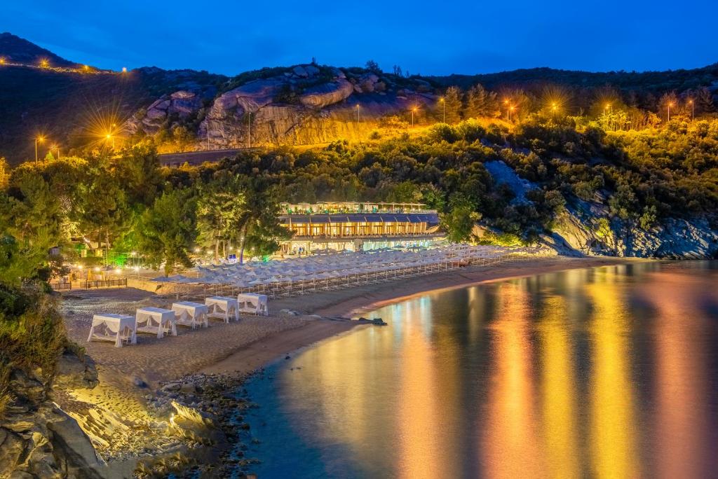 a group of white chairs on a beach at night at Tosca Beach Hotel in Paleo Tsifliki