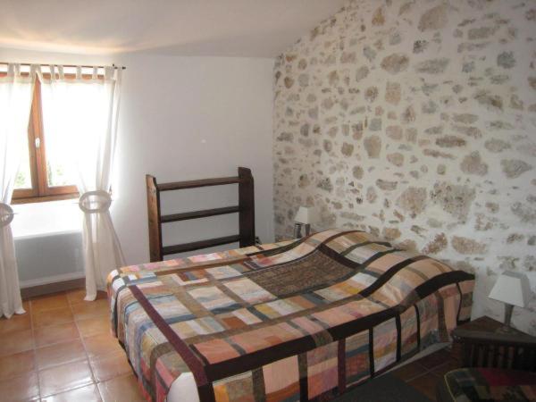 a bedroom with a bed and a stone wall at Les Gîtes du Lac - Appartements in Montauroux