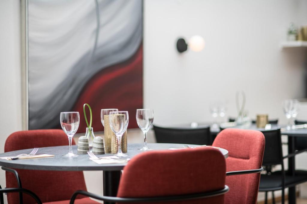 a table with wine glasses and red chairs at Quality Hotel Prisma in Skövde