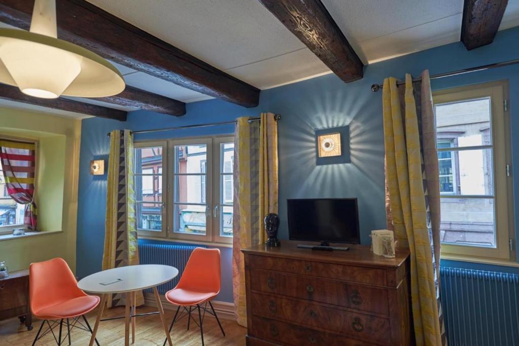 een woonkamer met een tv en een tafel en stoelen bij Maison Cliquot - Appartements Colmar Centre in Colmar