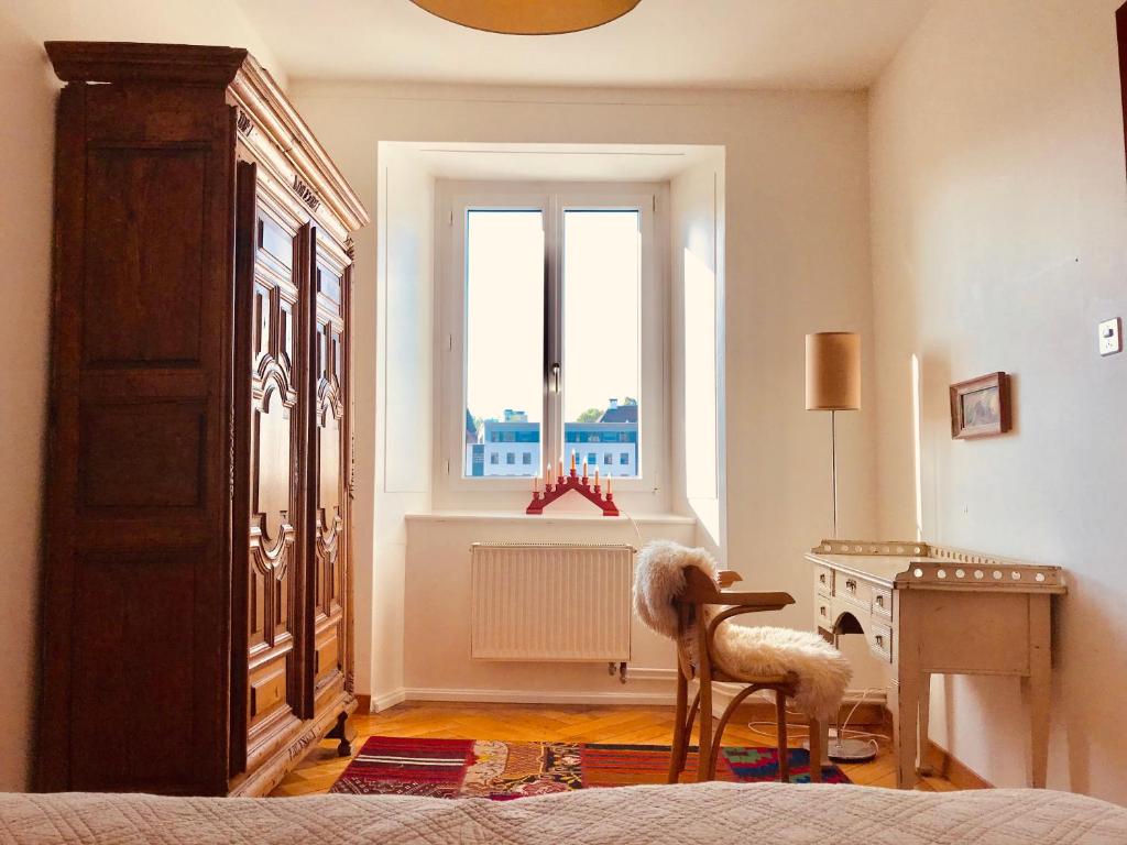 a bedroom with a bed and a desk and a window at Appartement 1Bijou in La Chaux-de-Fonds