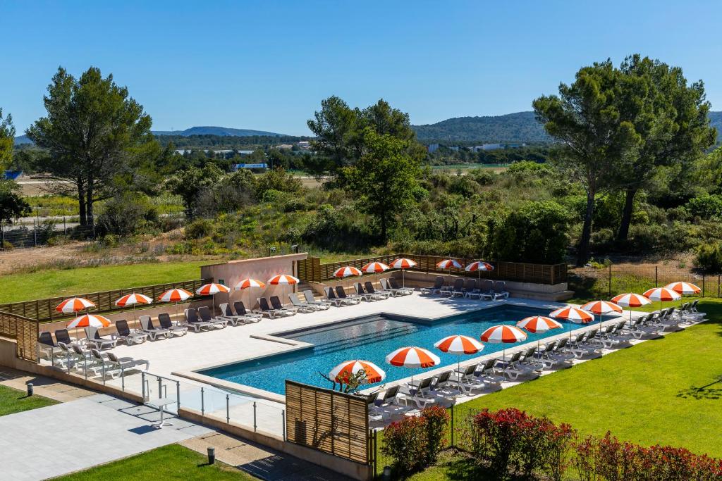 uma vista superior para uma piscina com guarda-sóis e cadeiras em Grand Prix Hôtel & Restaurant em Le Castellet