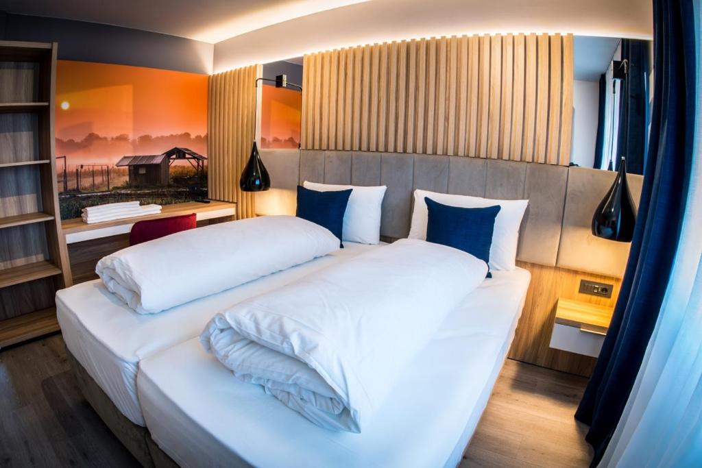 sypialnia z dużym białym łóżkiem z niebieskimi poduszkami w obiekcie Hotel Wilder Mann w mieście Rückersdorf