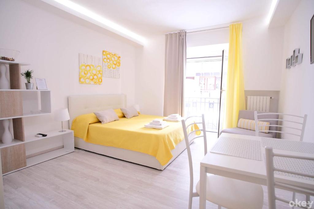 1 dormitorio con cama amarilla, mesa y sillas en Charme & Chic Studios - Bari Centro, en Bari