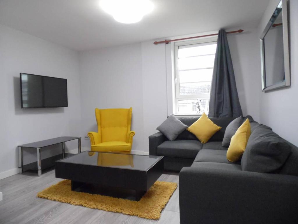 uma sala de estar com um sofá e uma cadeira amarela em Art Deco Building on Vibrant Sauchiehall Street em Glasgow