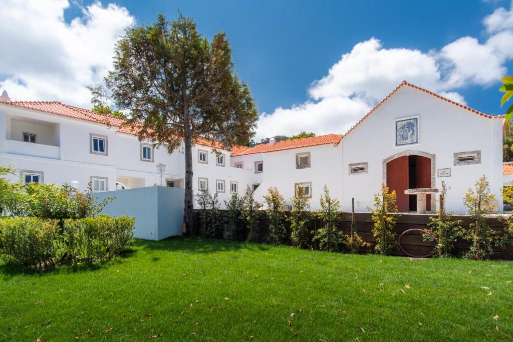 een groot wit gebouw met een groene tuin bij Quinta Pedra Firme in Sintra