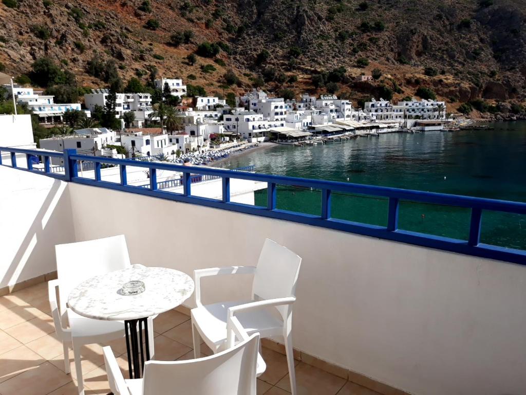 
a white chair sitting on top of a balcony overlooking the ocean at Loutro Holidays in Loutro
