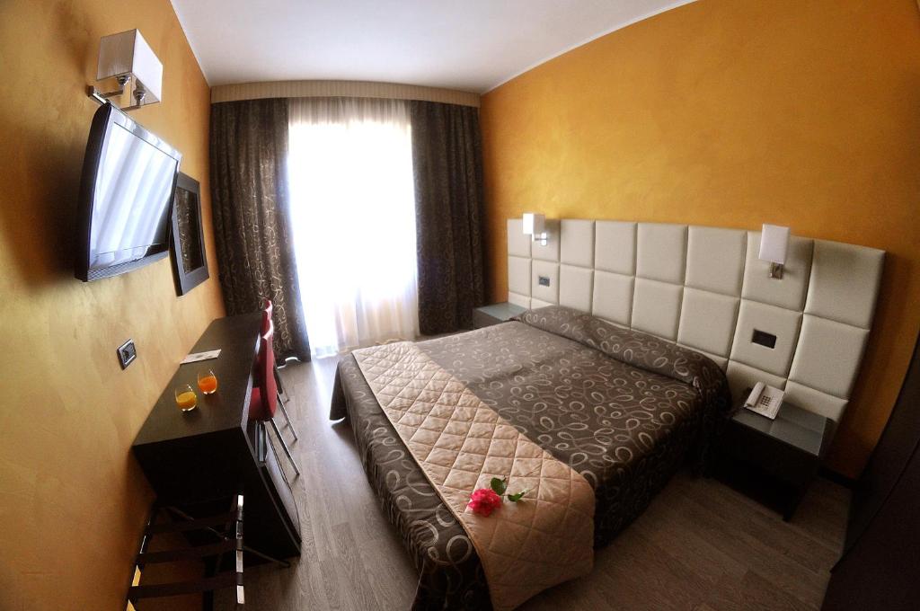 a bedroom with a bed and a window with a television at Hotel Cristallo in Varazze