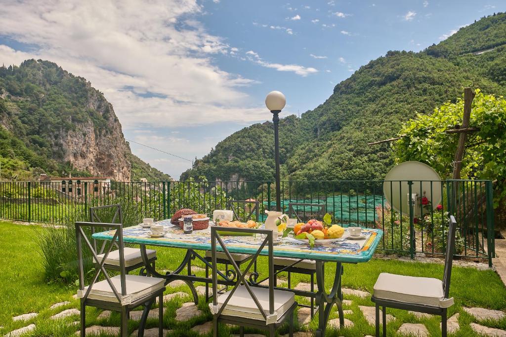 un tavolo con sedie e frutta con le montagne di Villa Pricitella ad Amalfi