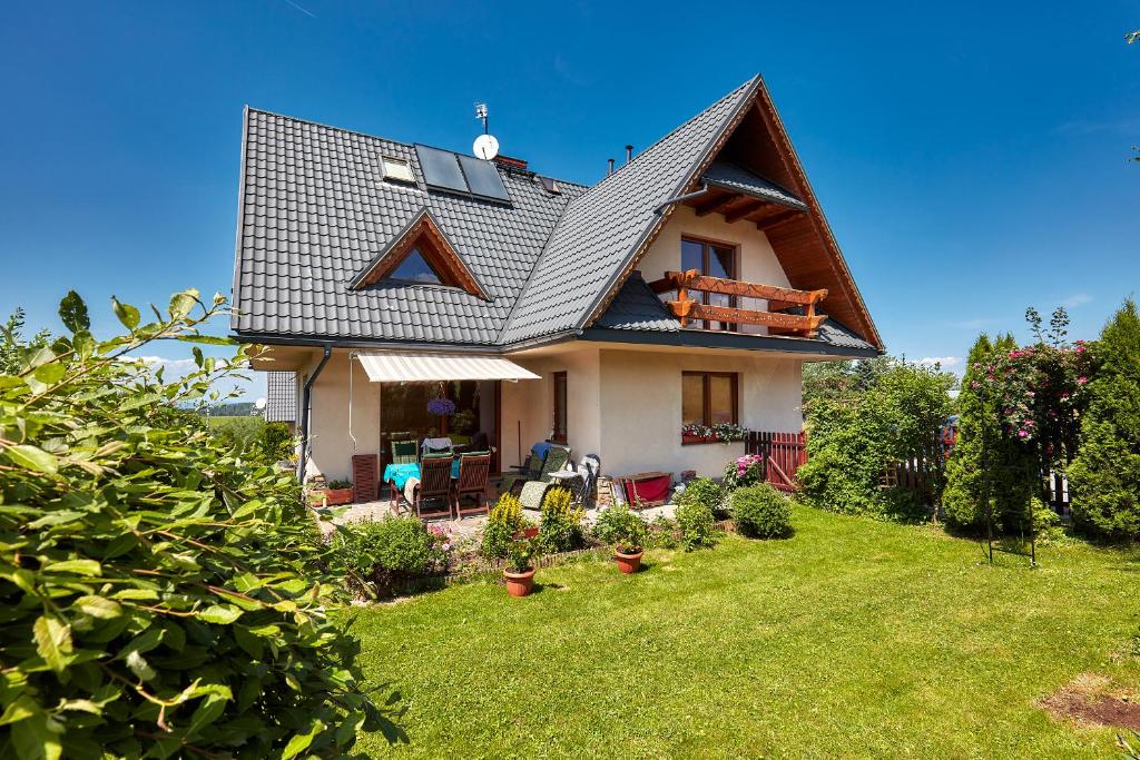 a house with a gambrel roof on top of a yard at Apartament 1010 m in Ząb
