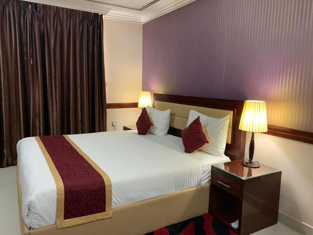 a bedroom with a large white bed with two lamps at Hala Inn Hotel Apartments - BAITHANS in Ajman 