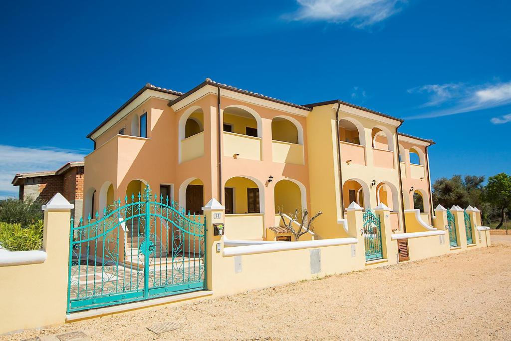 a large yellow house with a blue gate at Le Residenze del Maria Rosaria - Vico Friuli 1 in Orosei