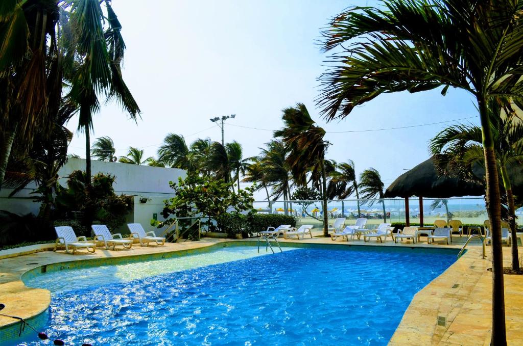 a beach with a pool, chairs, and a pool table at Hotel Playa Club in Cartagena de Indias