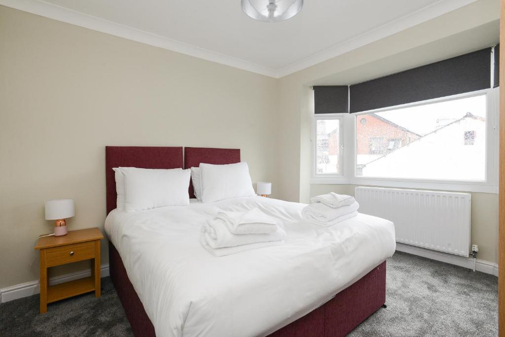 een slaapkamer met een groot wit bed en handdoeken bij Cosy House in the heart of Beeston with FREE Parking and WiFi in Nottingham