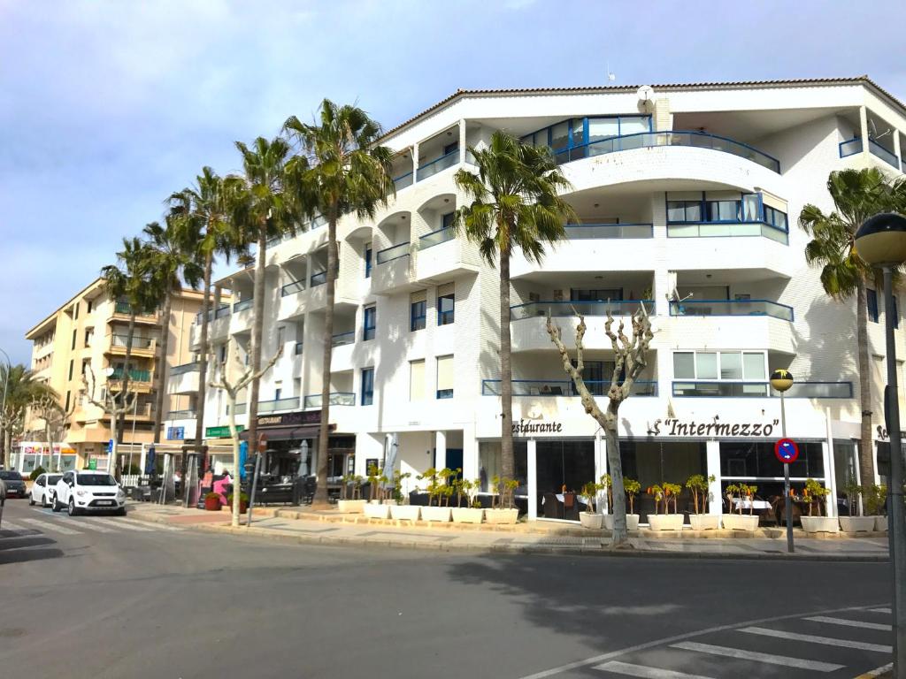 a large white building with palm trees in front of it at Albir Azul in Albir