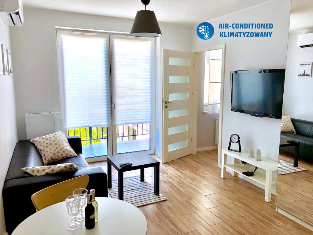 ein Wohnzimmer mit einem Sofa, einem TV und einem Tisch in der Unterkunft Apartament Poznańska24 in Bydgoszcz