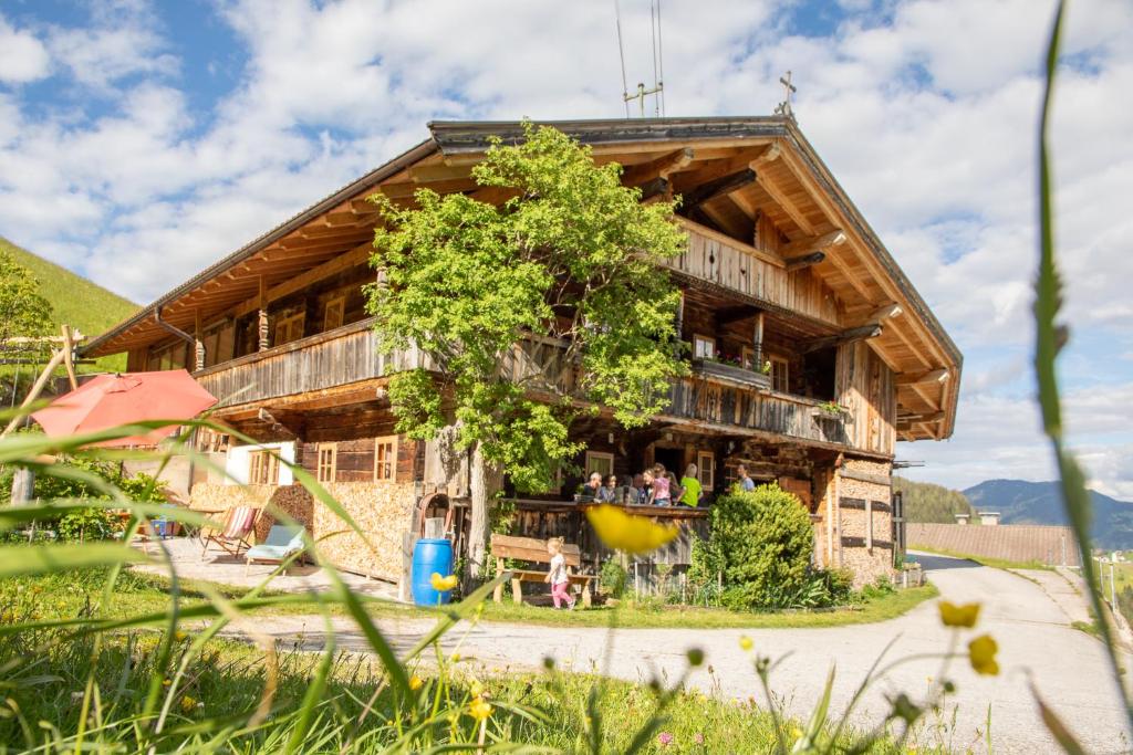 ein großes Holzgebäude mit Menschen auf dem Balkon in der Unterkunft Tradlhof in Thierbach