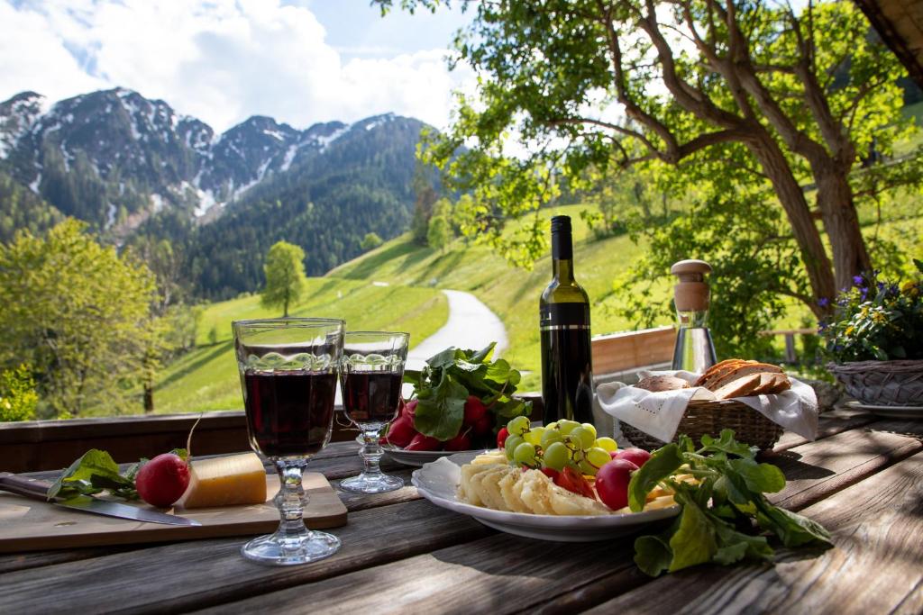 a table with a glass of wine and a plate of food at Tradlhof in Thierbach