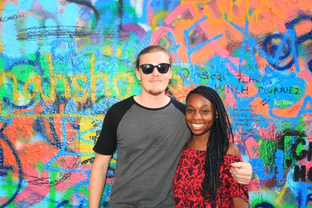 a man and a woman standing in front of a wall with graffiti at Ahoy! Hostel in Prague