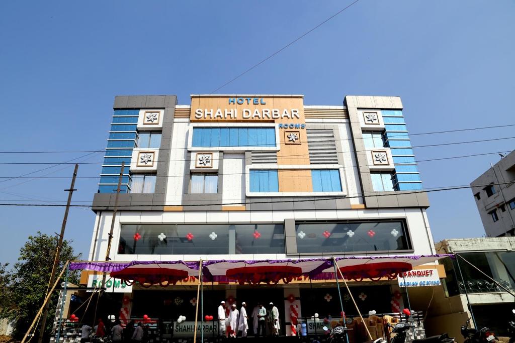 Un grand bâtiment avec un panneau en haut dans l'établissement Hotel Shahi Darbar, à Navsāri