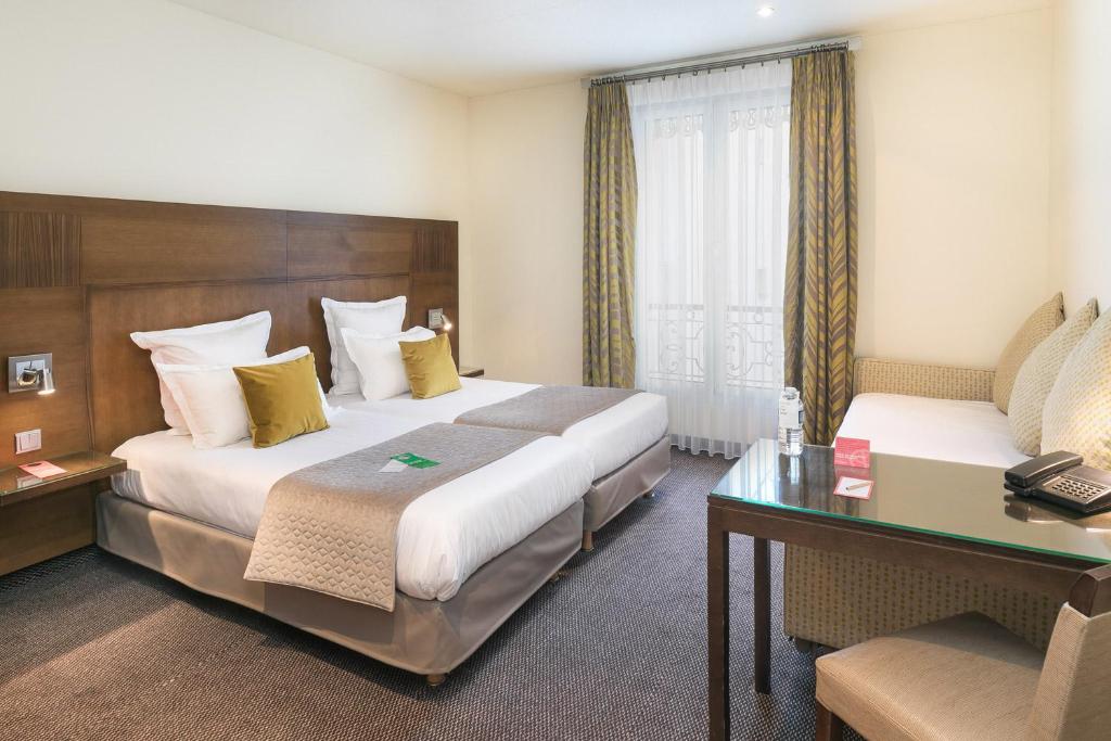パリにあるHôtel Le Cardinalのベッド2台とデスクが備わるホテルルームです。