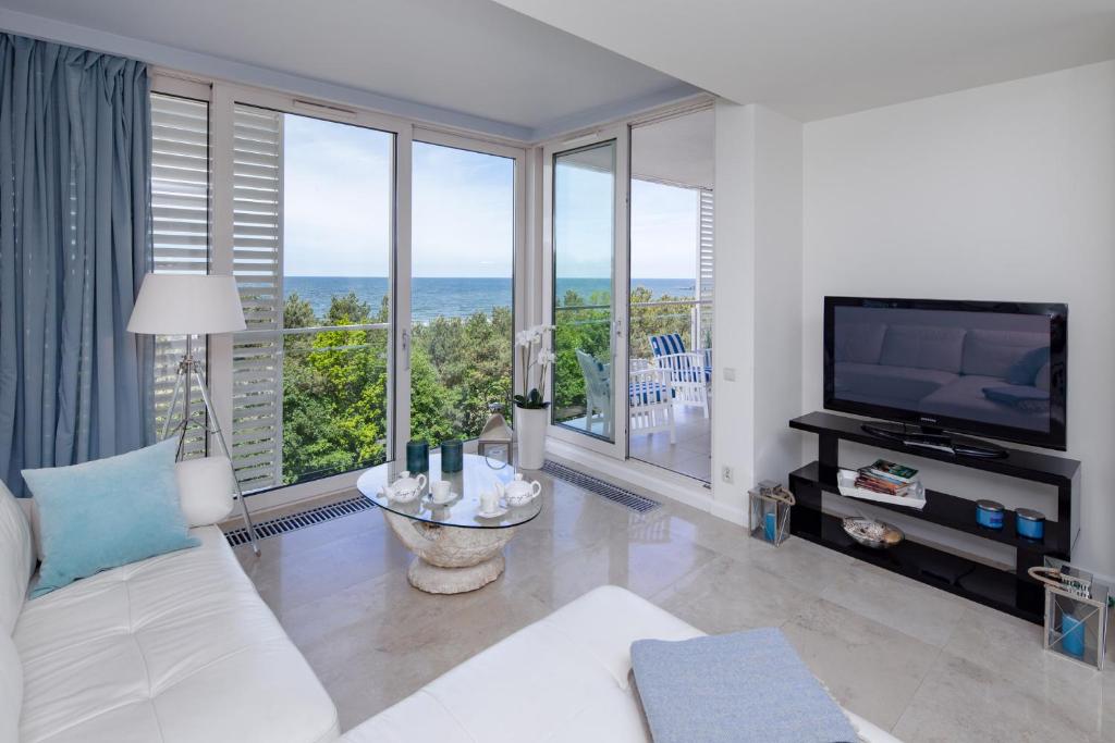 a living room with a white couch and a television at Apartament Playa Baltis 66 z widokiem na morze in Międzyzdroje