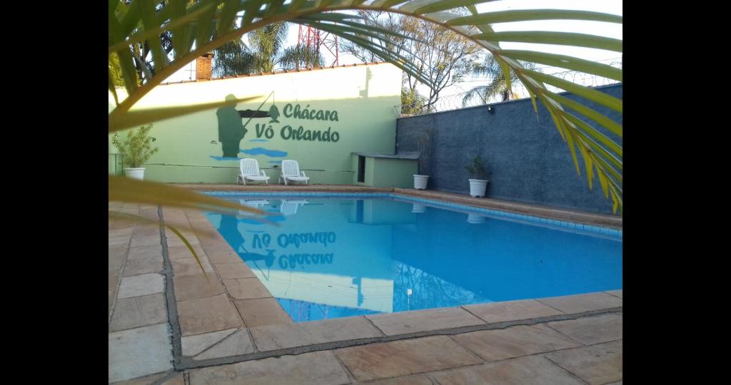 uma piscina com duas cadeiras ao lado de um edifício em Chácara Vô Orlando em Rio Claro