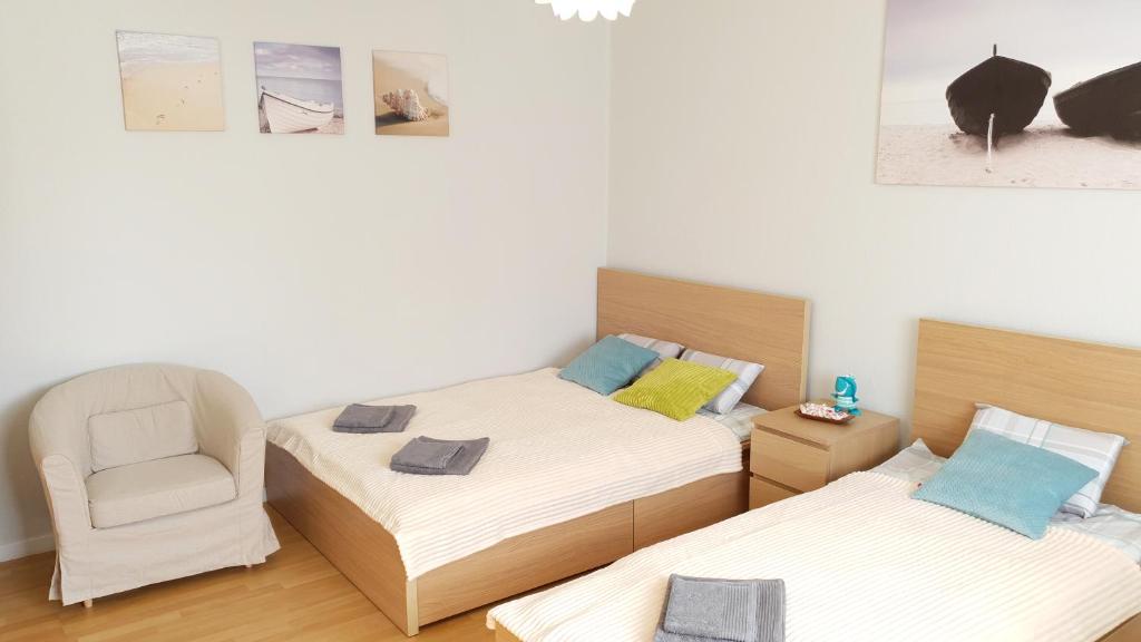 a bedroom with two twin beds and a chair at Apartament Miarki 3 in Świnoujście