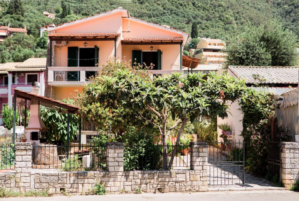 una casa con árboles frente a una valla en Theodora Corfu Holiday Apartments, en Ýpsos