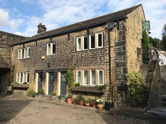 an old brick house with plants in front of it at Over The Bridge Guest House in Ripponden