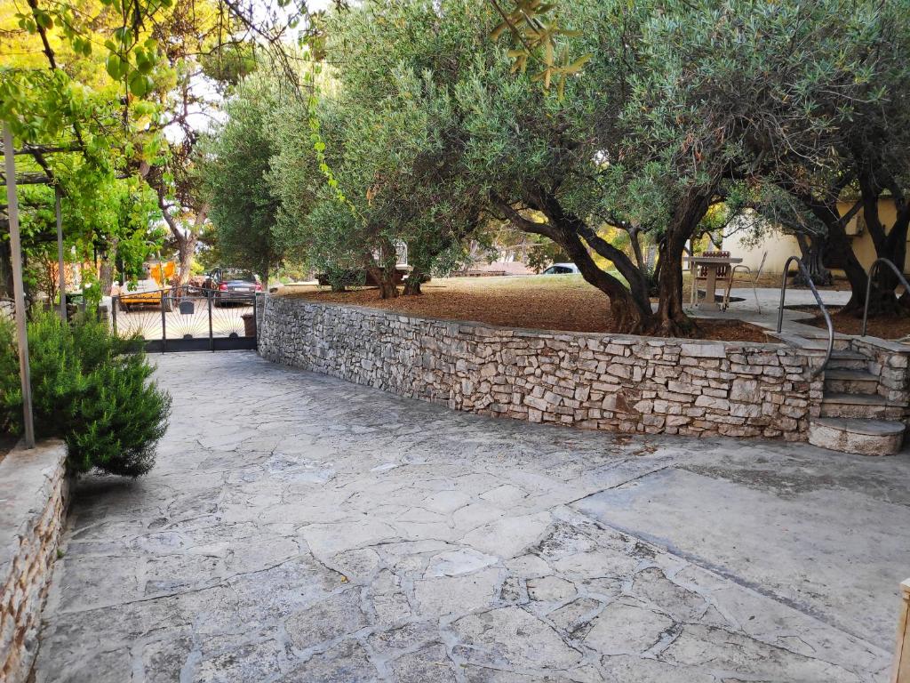 a stone retaining wall and trees in a park at Apartments Vrsalovic in Bol