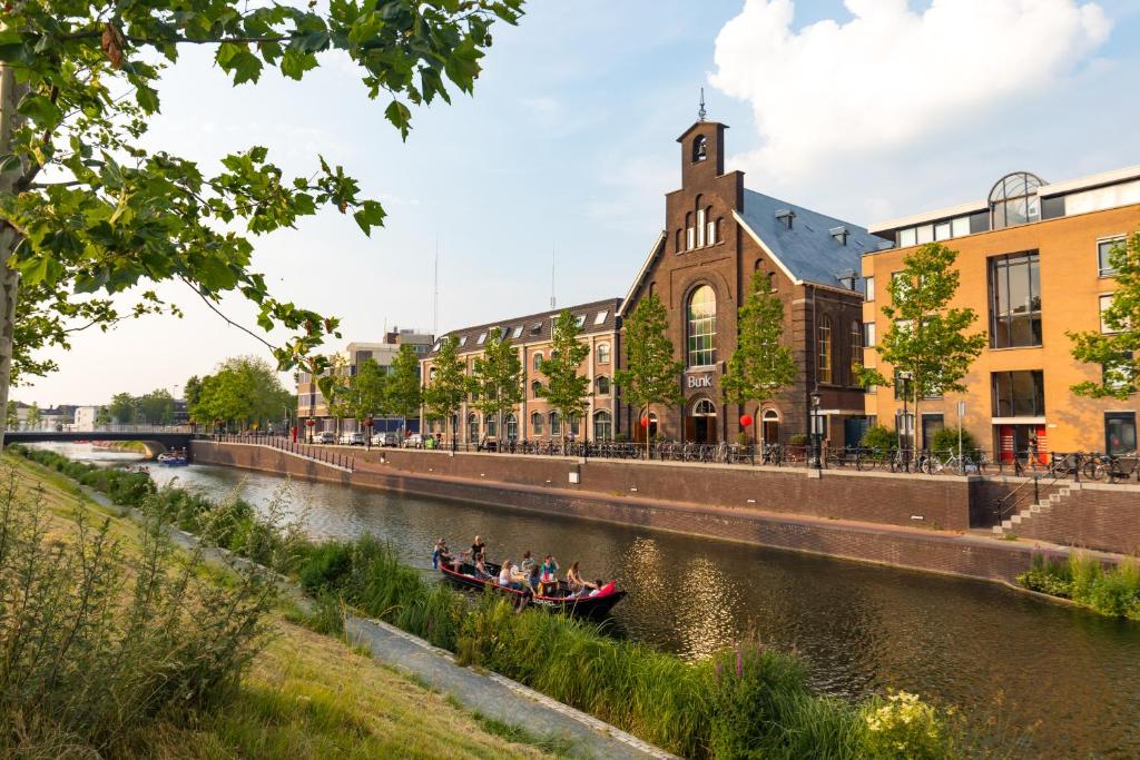 people in a boat on a river in front of a building at BUNK Hotel Utrecht in Utrecht