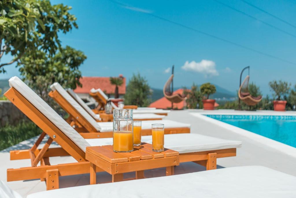 uma mesa com dois copos de sumo de laranja ao lado de uma piscina em Villa Mina em Kotor