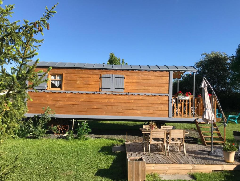 ein winziges Haus mit einer Terrasse und einem Tisch in der Unterkunft La roulotte au fond du pré in Coltines