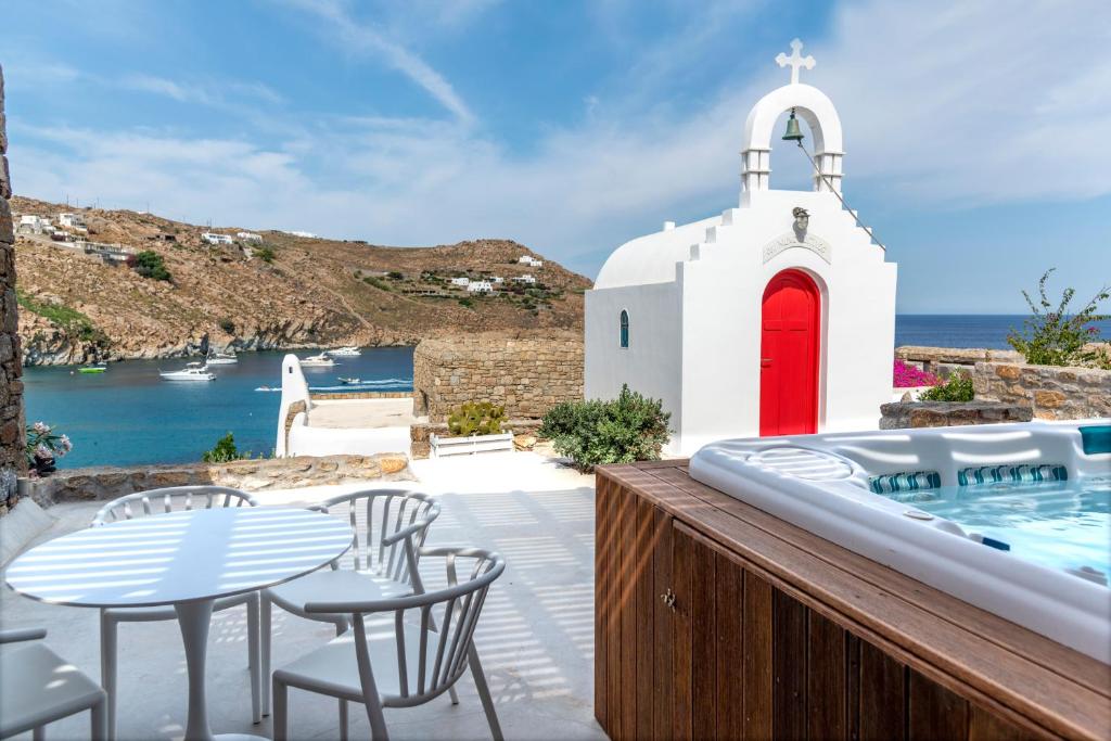 a white church with a red door and a swimming pool at Etesians Suites & Villas in Super Paradise Beach