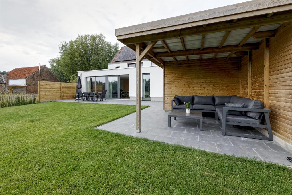 a patio with a black couch under a pavilion at Aan de duinbossen in De Haan