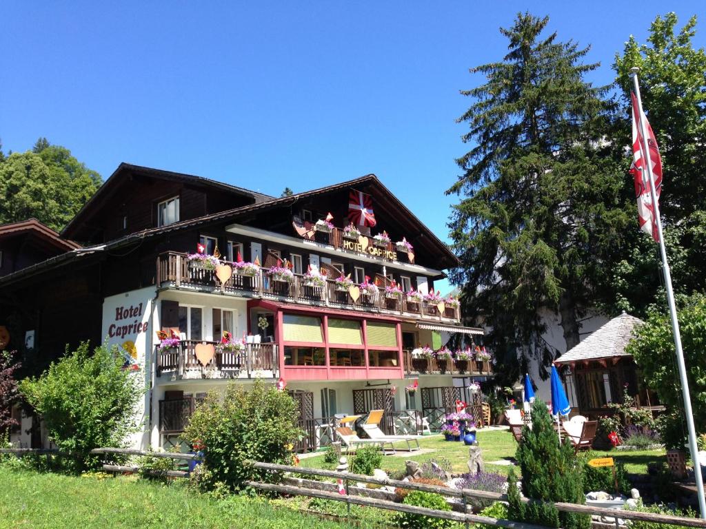 a building with a bunch of flowers on the balconies at Hotel Caprice - Grindelwald in Grindelwald