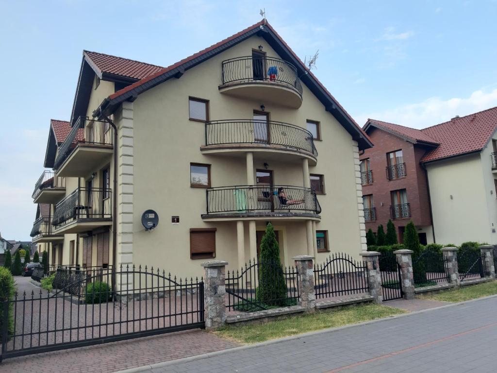 a white building with balconies and a fence at Apartament Piotr in Łeba