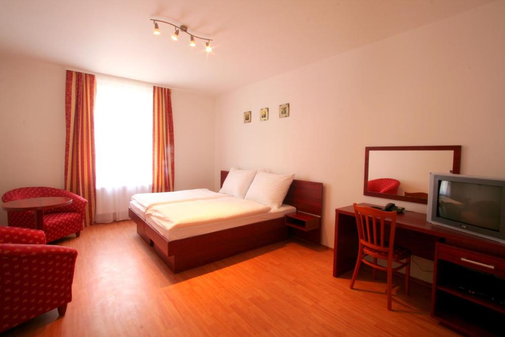 プラハにあるアパート ホテル スサのベッドとテレビが備わるホテルルームです。