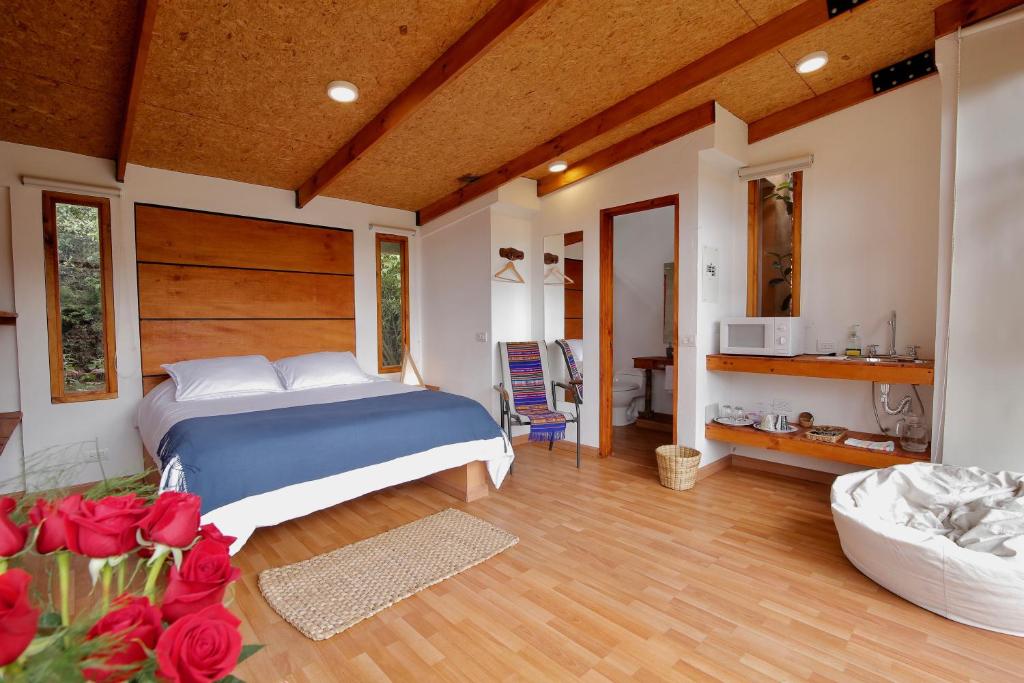 Un dormitorio con una cama y rosas rojas. en Titué Refugio , Cabañas en La Calera