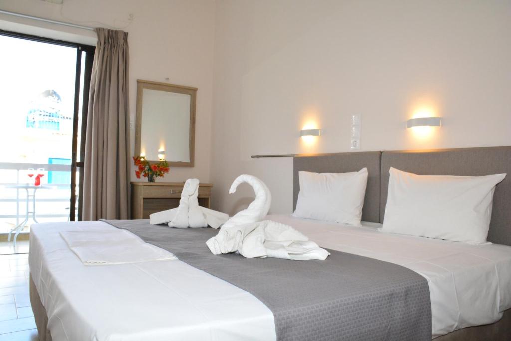 two swans sitting on a bed in a hotel room at GOLDEN STAR in Agia Marina Aegina