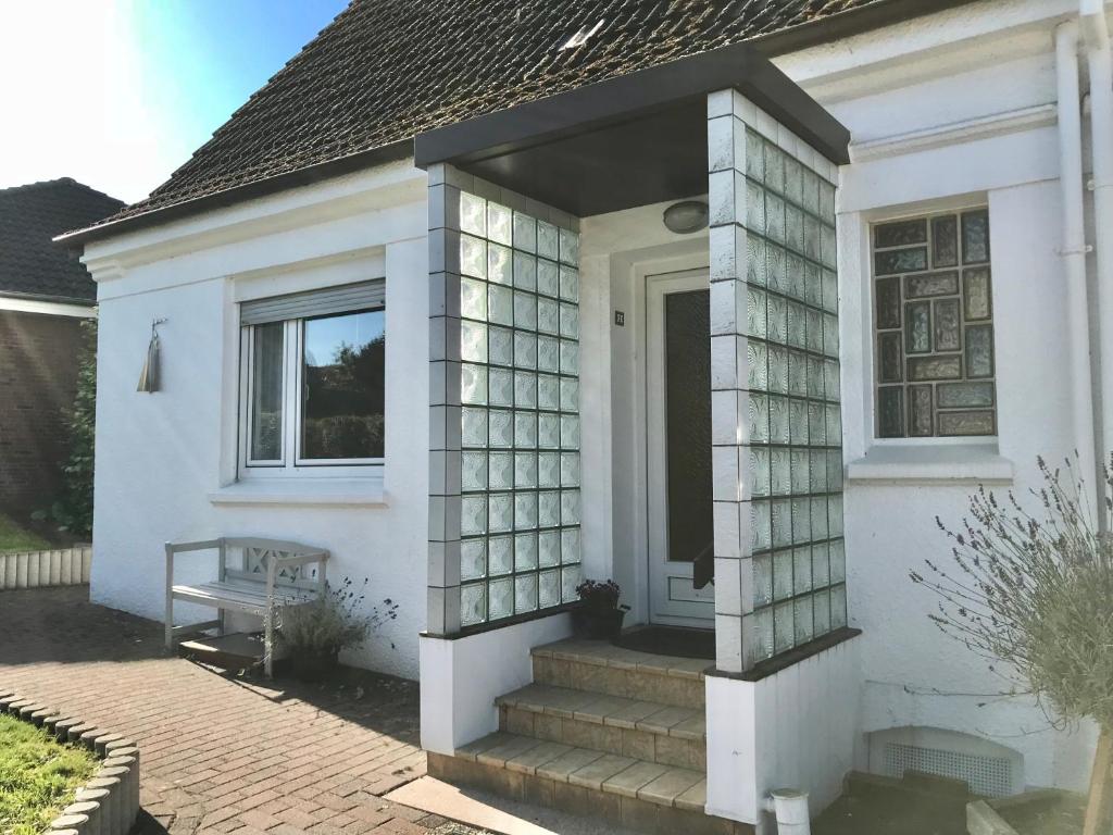 a white house with a glass door and stairs at Liegeplatz TWEE in Laboe