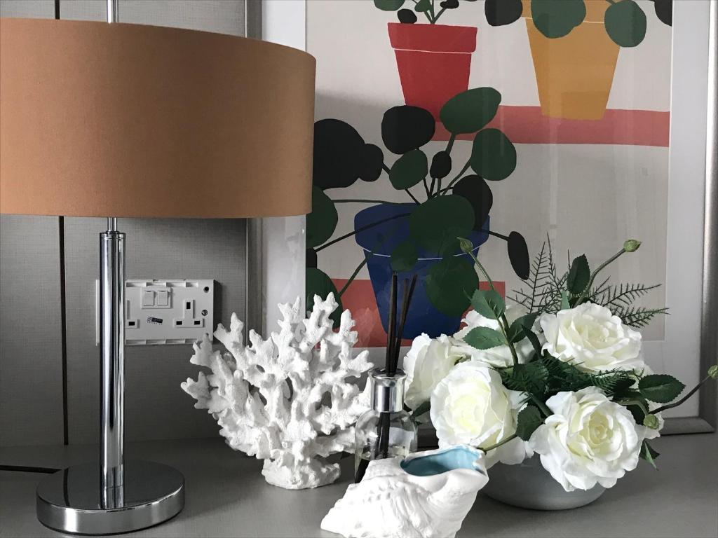 eine Lampe und eine Vase Blumen auf dem Tisch in der Unterkunft Levante Holiday Apartments in Larnaka