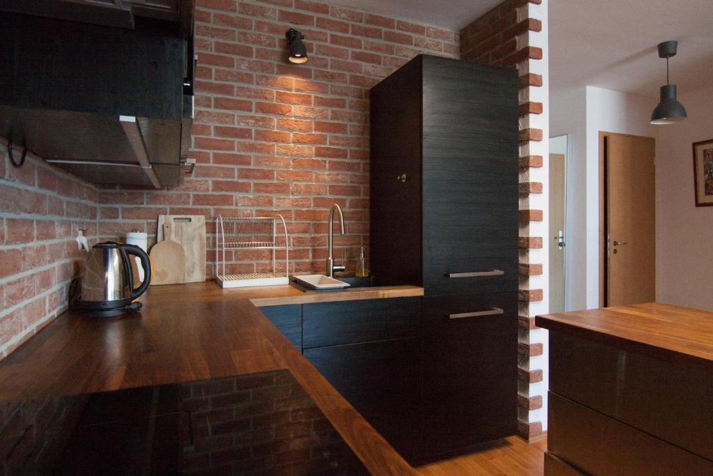 a kitchen with black cabinets and a brick wall at Bajka 09 -Self Check - Free parking in Bratislava