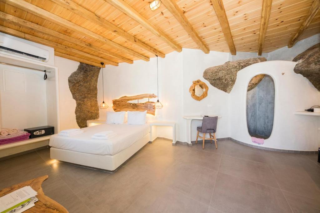 a bedroom with a white bed and a rock wall at Sahas Suites in Mýkonos City